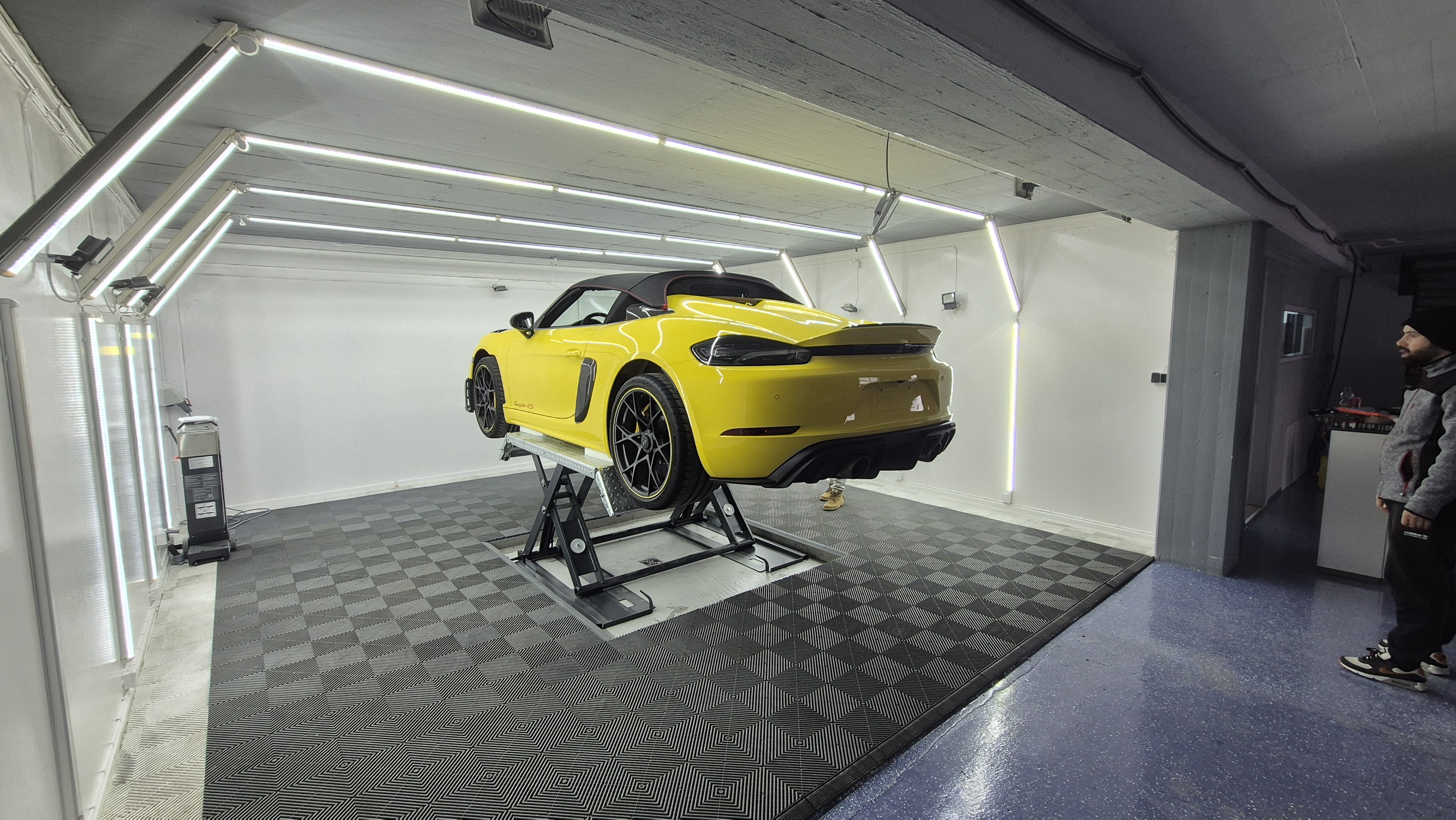 ES Autopflege Mitarbeiter bei der Arbeit am Porsche 718 Spyder RS auf der Hebebühne